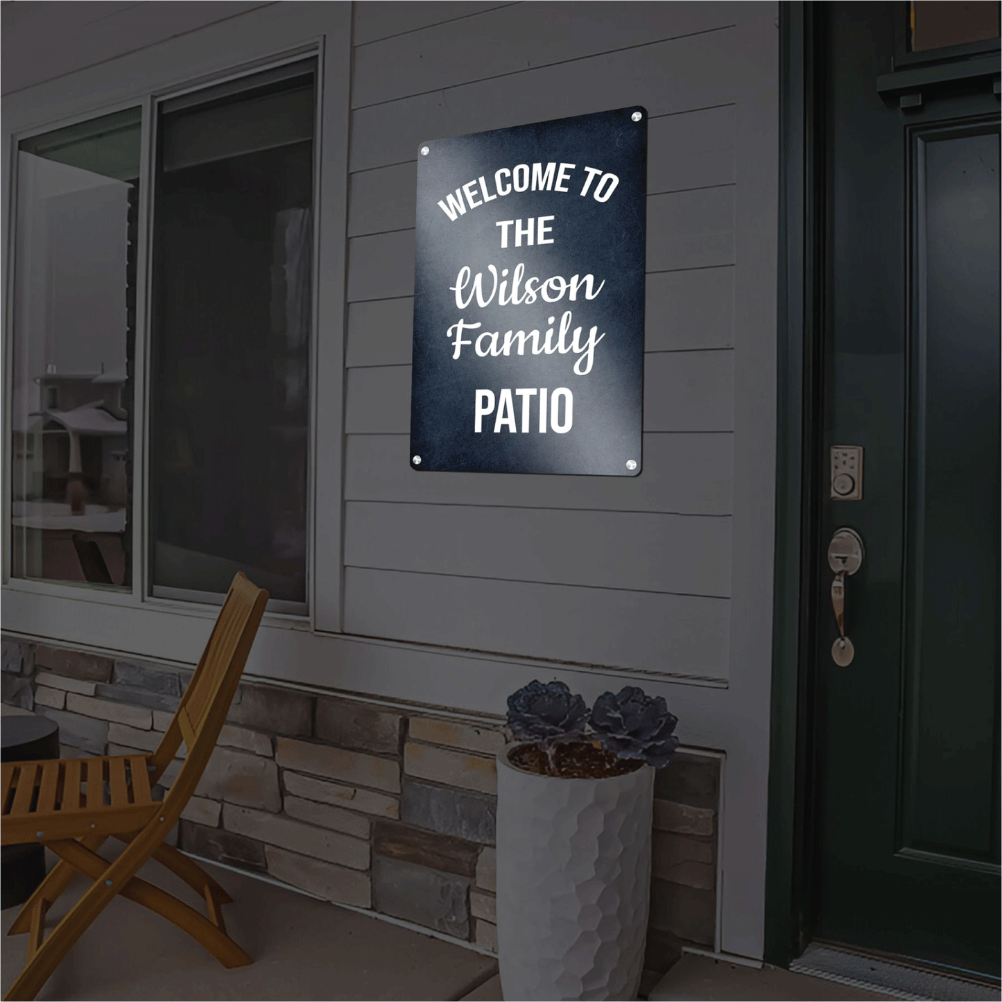 Custom dark blue reflective aluminum sign reading Welcome to the Wilson Family Patio in elegant white script, mounted outdoors on a home's siding next to a doorway.