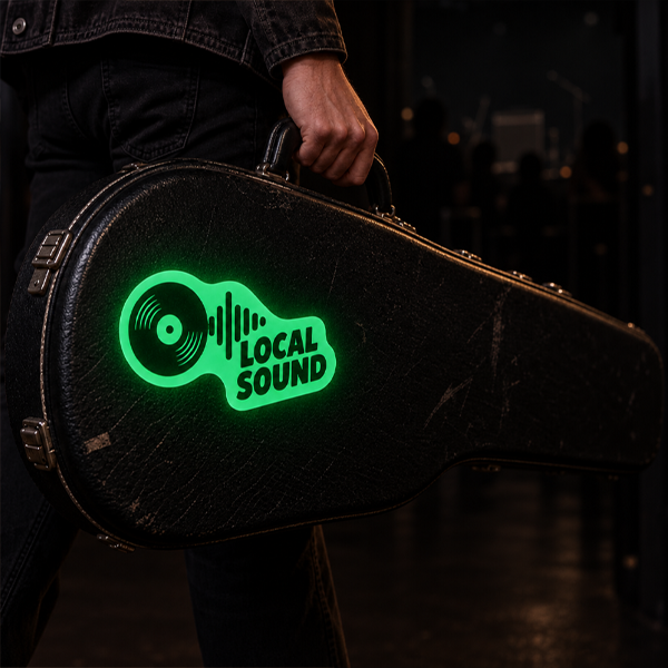 A person holding a black guitar case with a glowing green vinyl record logo and the words 'LOCAL SOUND' on the front, set against a dark stage-like background.