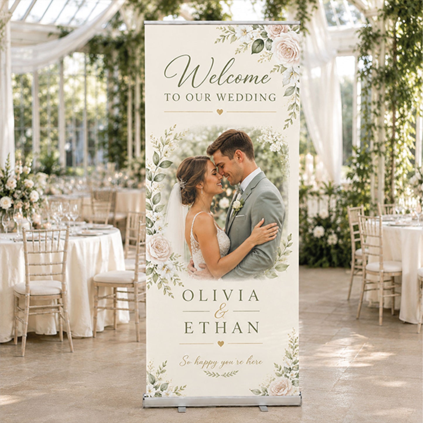 A personalized vertical roll-up banner stand displayed in a wedding reception hall. The banner features a custom printed design with a couple's wedding photo, floral watercolor borders, and the text 'Welcome to our wedding' and 'Olivia & Ethan'.