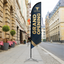 Beef Steak custom angled feather flag with black cross base displayed outdoors on a city street.