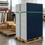 A large stack of white textured yard sign stakes wrapped vertically with a green strap, standing on a wooden pallet in a warehouse setting. Cardboard boxes labeled 'Yard Sign Stakes' are visible in the background on pallets.