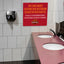 ⁠A red commercial PVC plastic sign mounted on a tiled restroom wall above a sink countertop.⁠