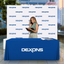 Custom blue 4-foot table throw with business logo paired with a white step and repeat backdrop.
