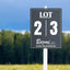 Black and white custom corrugated plastic lot sign mounted on a white stake in a field.