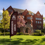 A maroon custom feather flag with "Admission Open" text standing on a green grass lawn in front of a brick campus building.⁠