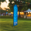 Blue Econo feather flag sign standing on a grass lawn with a blurred outdoor event background.
