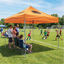Orange custom canopy tent set up at an outdoor community sports event.