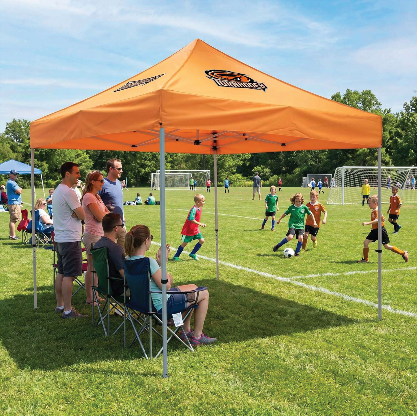 Orange custom canopy tent set up at an outdoor community sports event.