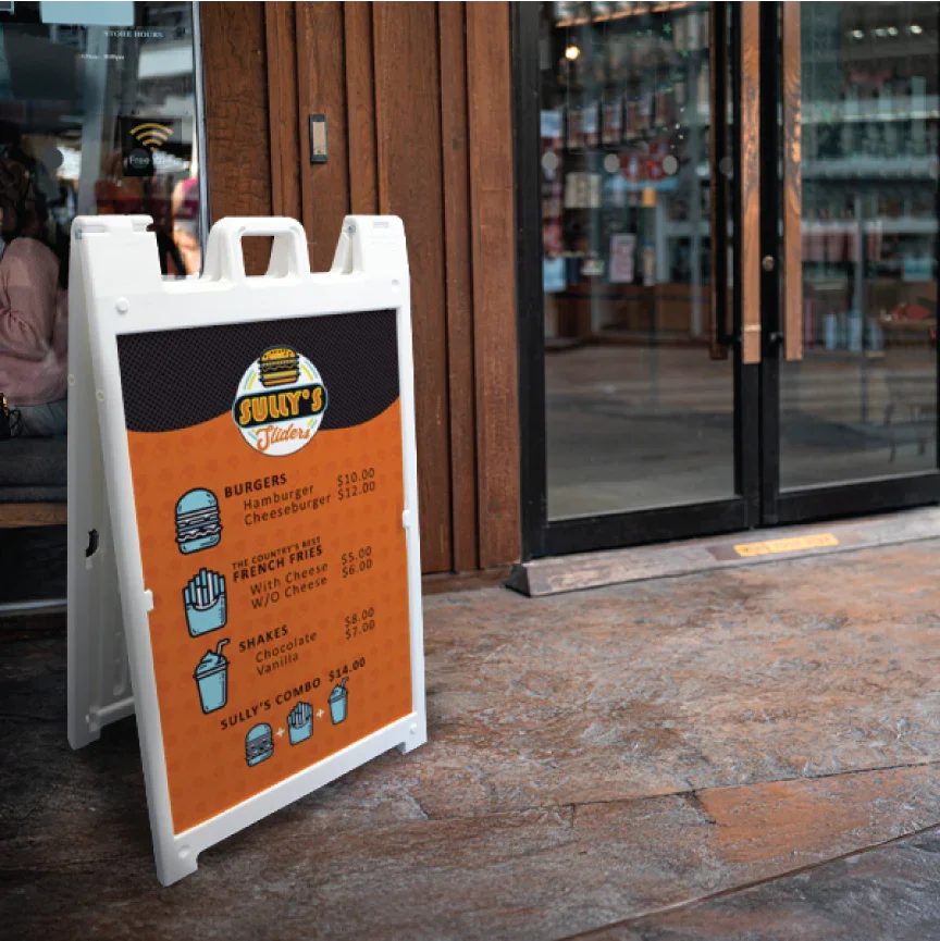 Durable white plastic A-frame sidewalk sign featuring a bold orange "Now Open" graphic on a brick sidewalk exterior.