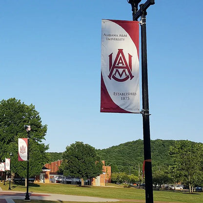 A red and white university campus avenue pole banner sign mounted high on a black lamppost outdoors.⁠