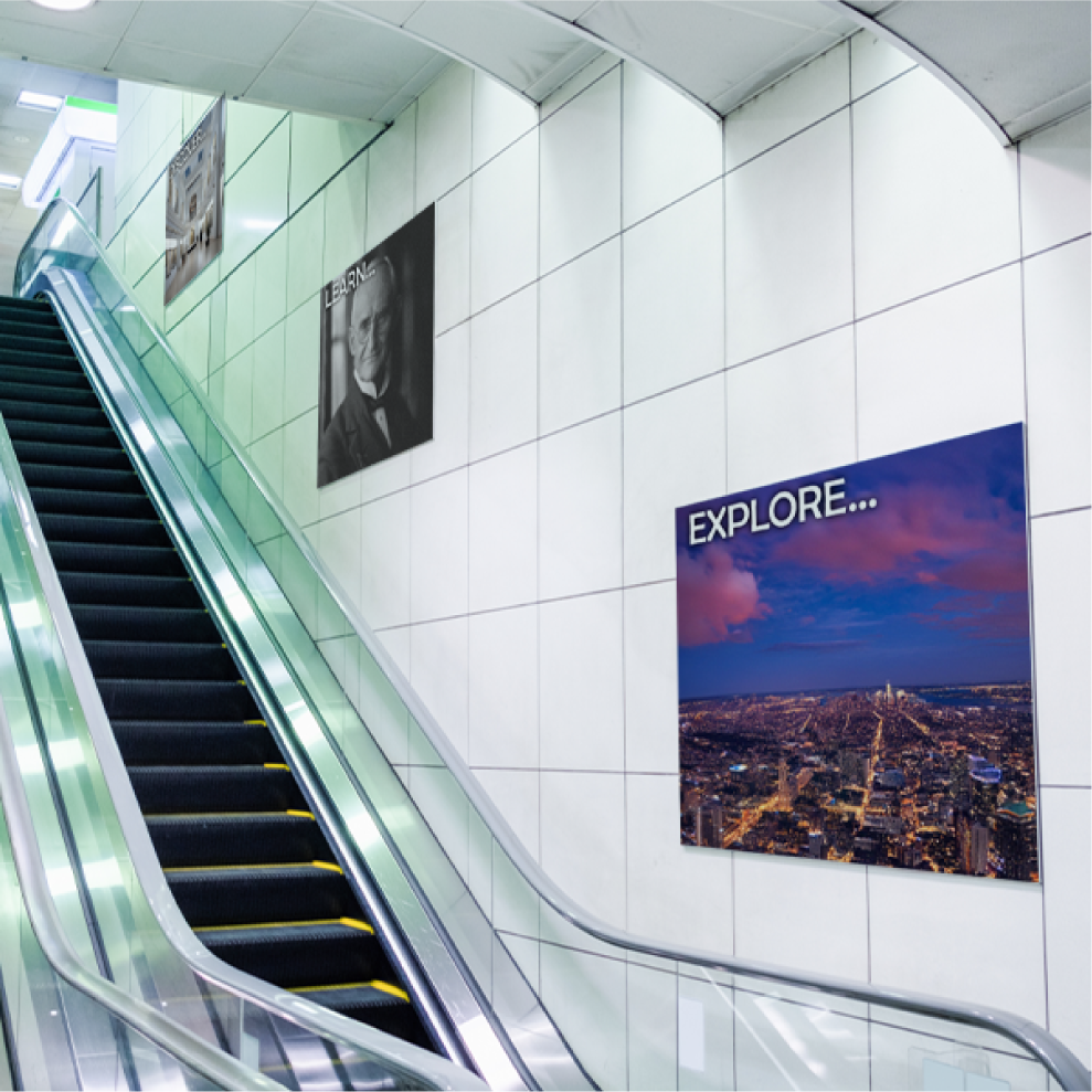 Multiple custom printed PVC Sintra board signs mounted for advertising along a commercial tiled wall next to an escalator.⁠