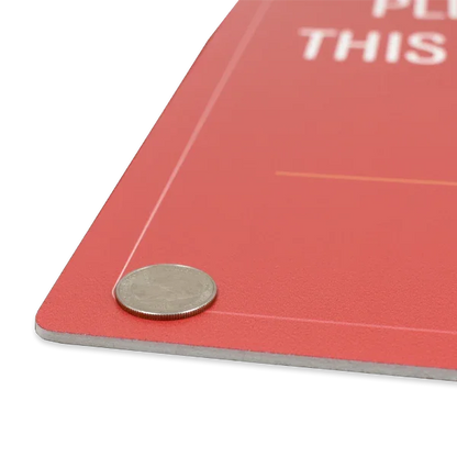 Close-up shot of a red rigid PVC plastic sign with a quarter placed on top to illustrate material thickness and durability.⁠