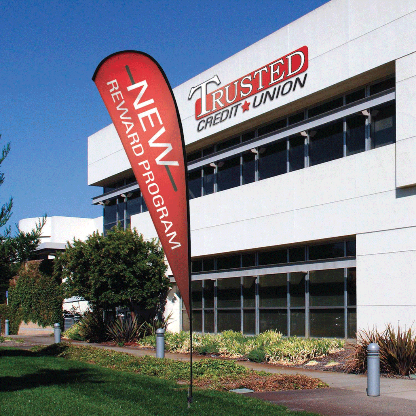 A bright red custom teardrop flag banner reading "NEW REWARD PROGRAM" standing outside a Trusted Credit Union building.